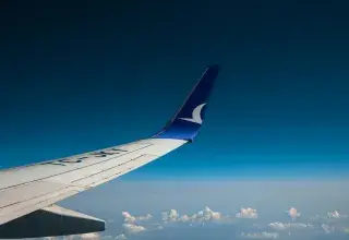Aile d'avion survolant les nuages et la terre