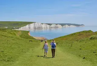 Deux hommes debout sur un terrain herbeux près d'un plan d'eau pendant la journée