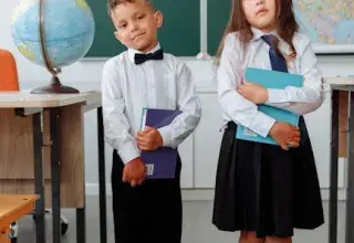 Deux enfants en uniforme scolaire tenant des livres dans une salle de classe