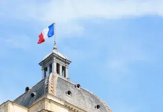 Le drapeau français flotte au sommet d'un dôme d'architecture historique à Paris