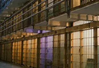 Intérieur sombre d'un bloc cellulaire de prison, montrant des rangées de barreaux d'acier