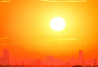 A city skyline silhouetted against a vivid, orange sunset sky.