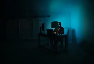 man sitting facing laptop — cybersécurité
