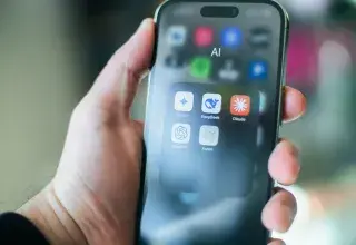 A hand holds a smartphone with various AI apps