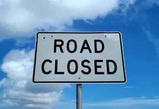 a road closed sign in front of a blue sky