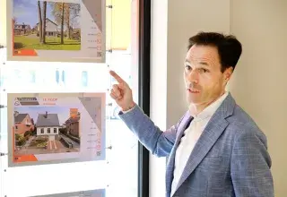 Man pointing at property listings displayed in a window.