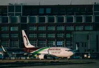Royal Air Maroc aircraft parked at an airport apron with terminal building in the background.