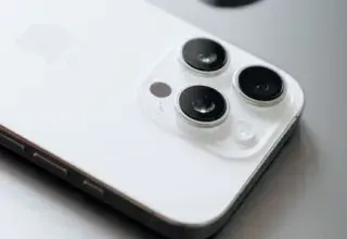 White smartphone with triple cameras lies atop a sleek laptop.