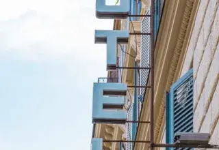 Classic vertical shot of Hotel Saturnia sign and shutters on brick facade.