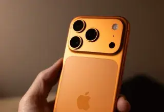 Orange smartphone with triple camera system held.