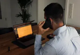 man in blue dress shirt holding black smartphone