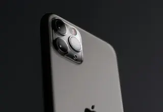 A grey smartphone with a triple camera array against a dark background