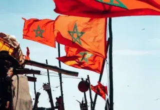 Colorful Moroccan flags waving by the ocean, symbolizing national pride and coastal culture.