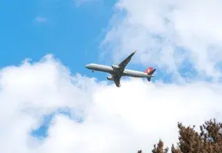 A commercial airplane glides through a clear blue sky with scattered clouds, capturing the essence of aviation travel.