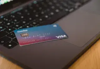 A blue and red gradient debit card resting on a dark laptop keyboard