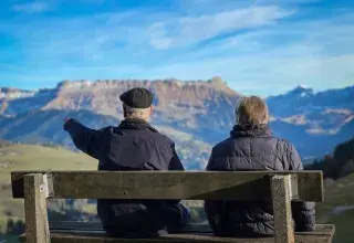 Senior couple sits on bench admiring Swiss Alps landscape in Lucerne.