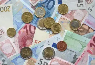 Pièces et billets en euros étalés sur une table, symbole du salaire minimum