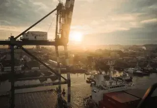Grue et navires de charge dans un port au coucher du soleil