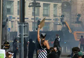 Manifestant debout sur une poubelle brandissant une pancarte lors d'une manifestation de rue