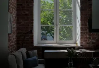 Salon lumineux avec canapé et grande fenêtre, illustration d’un logement de vacances