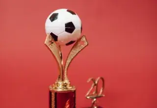 Trophée de football doré surmonté d'un ballon