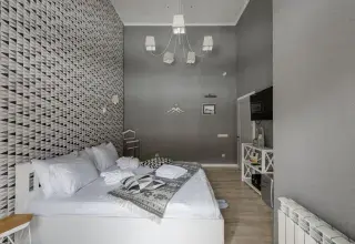 Chambre d’hôtel lumineuse avec lit blanc, plaid et mur à motifs géométriques