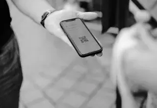 Une main tient un smartphone qui affiche un QR code
